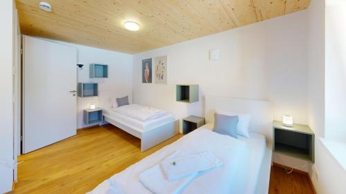 a bedroom with a white bed and a wooden ceiling at HEIMATEL - Ferienhaus Prinz-Lui in Scheidegg