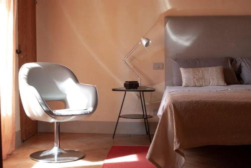 a bedroom with a white chair next to a bed at Casa Sant Angelo in Sarteano