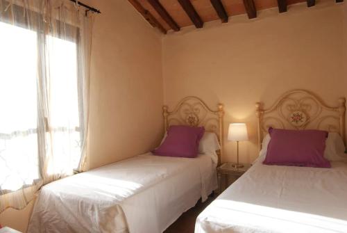 a bedroom with two beds with purple pillows and a window at Casa Sant Angelo in Sarteano