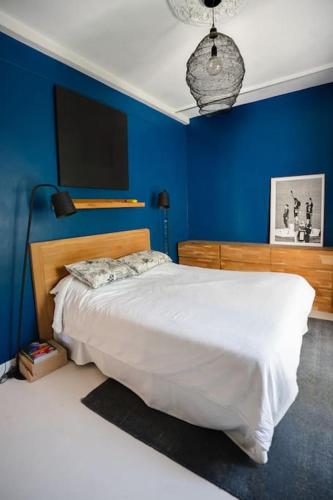 une chambre avec un grand lit aux murs bleus dans l'établissement Agréable Maison Contemporaine en Provence, à La Mérindolle