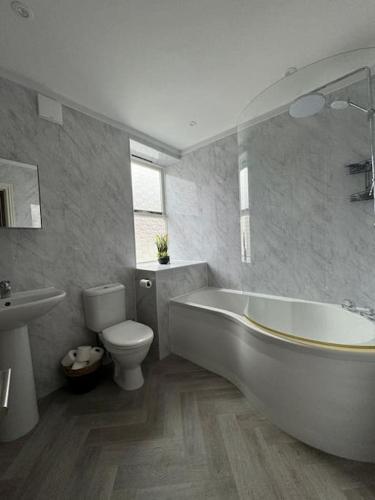 a bathroom with a white tub and a toilet at Townhouse in Weymouth, Dorset in Melcombe Regis
