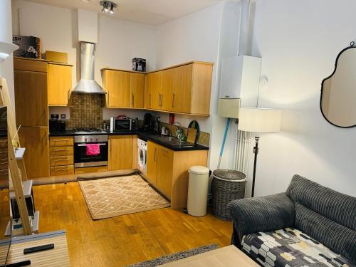 a kitchen with wooden cabinets and a couch in a living room at Entire 1 bed flat in the heart of London Islington in London