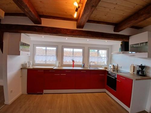 a kitchen with red cabinets and two windows at Ferienwohnung Ornela in Eggolsheim