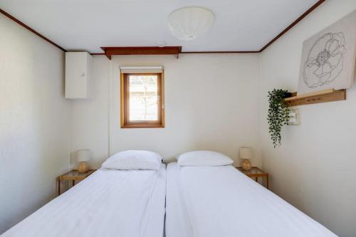 two beds in a white room with a window at Chalet omringd door groen op de Veluwe in Putten