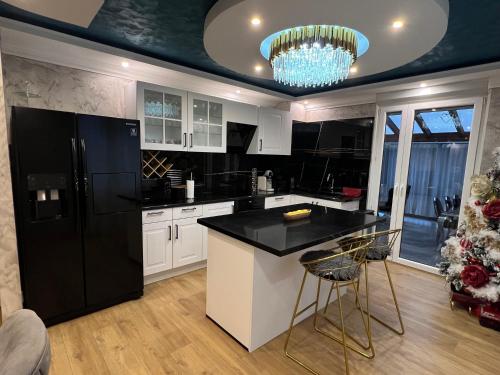 Il comprend une cuisine équipée d'un réfrigérateur noir et de placards blancs. dans l'établissement Maison De Luxe Pour 14 personnes - SPA - Billard - Sport - Baby-foot, à Le Tholy