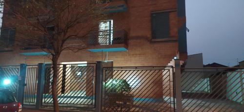 a fence in front of a brick building with a tree at Apartamento Espaçoso Bairro Piracicamirim in Piracicaba