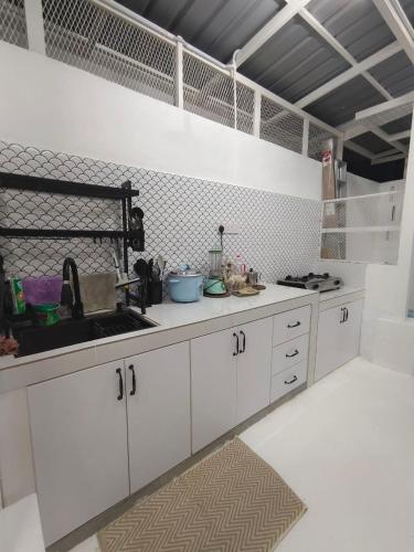 a kitchen with white cabinets and a sink at RUMAH ADAM Homestay Bukit Changgang Private Pool in Kampong Kubang Beras
