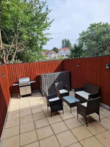 a patio with chairs and tables and a fence at Cozy flat & Lovely garden, High Speed WiFi in Cranford