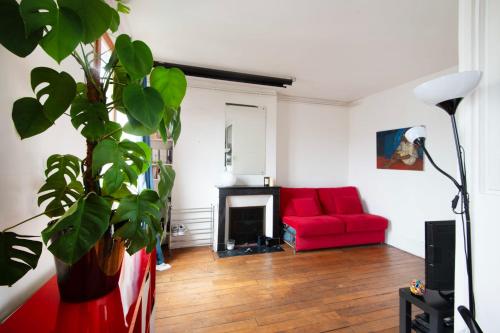 un salon avec un canapé rouge et une plante dans l'établissement Charming Studio near Le Marais and Bastille, à Paris