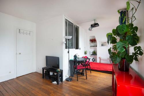 - un salon avec un lit et une table avec une télévision dans l'établissement Charming Studio near Le Marais and Bastille, à Paris