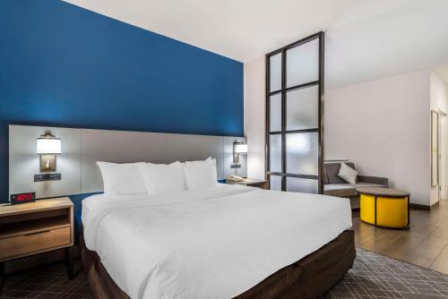 a large bed in a hotel room with a blue wall at Comfort Suites Macon Northwest in Macon