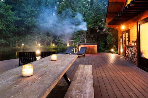 a wooden deck with a table and benches on it at ZenCabin - Luxe en Wellness in de natuur in Hulshout