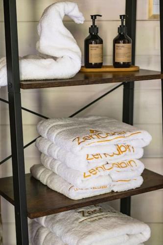 a towel rack with towels and bottles on it at ZenCabin - Luxe en Wellness in de natuur in Hulshout