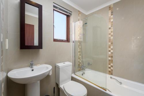 a bathroom with a toilet and a sink and a tub at San Lameer Villa's in Southbroom