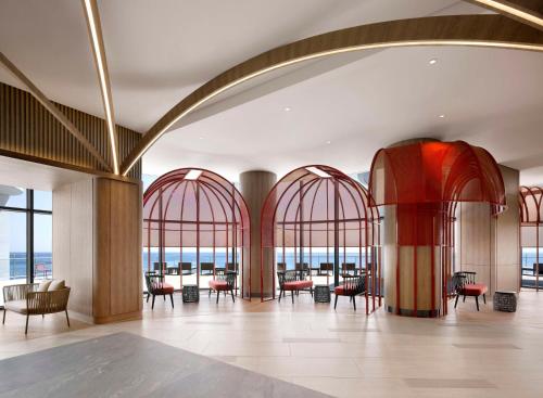 a lobby with red arches and tables and chairs at Cassia Sokcho in Sokcho