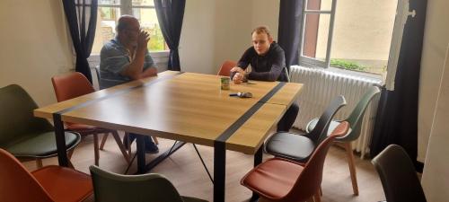 deux hommes assis à une table dans une pièce dans l'établissement le 52 guesthouse, à Neuvy-sur-Loire