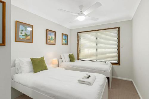 a white room with two beds and a window at Family Coastal Escape Narrawallee NSW in Narrawallee