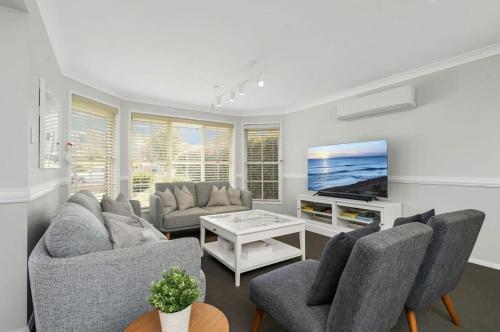 a living room with a couch and a tv at Basin Breeze Retreat Sanctuary Point in Sanctuary Point