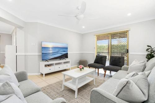 a living room with white furniture and a flat screen tv at Basin Breeze Retreat Sanctuary Point in Sanctuary Point