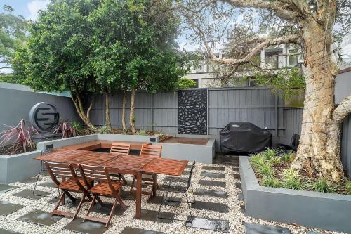 a patio with a wooden table and chairs and a tree at Balmain Garden Hideaway with BBQ in Sydney
