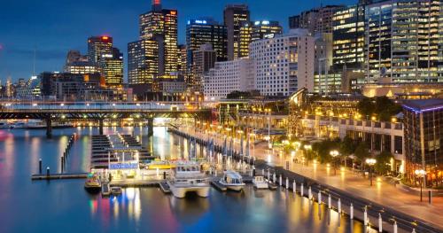 a city skyline at night with boats in the water at Balmain Garden Hideaway with BBQ in Sydney