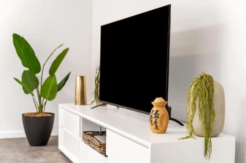 a tv on a white entertainment center with plants at Modern Balmain Abode in Sydney