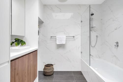 a white bathroom with a shower and a sink at Modern Balmain Abode in Sydney