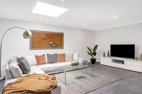 a white living room with a white couch and a tv at Modern Balmain Abode in Sydney
