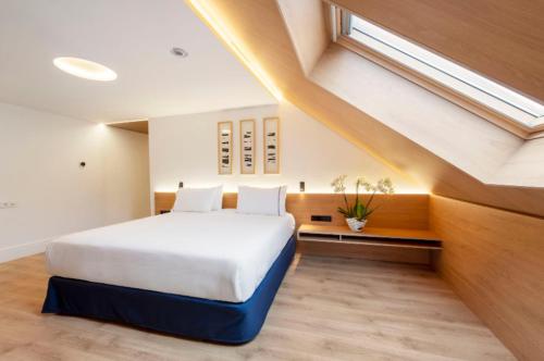 a bedroom with a large white bed with a window at Eurostars Pórtico Alicante in Alicante