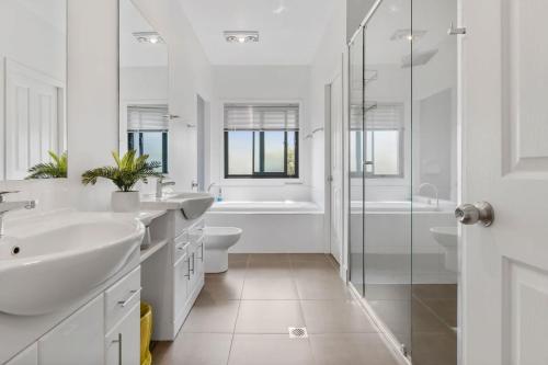 a white bathroom with two sinks and a shower at Breath taking Bay Views Private Pad Spacious in Morisset East