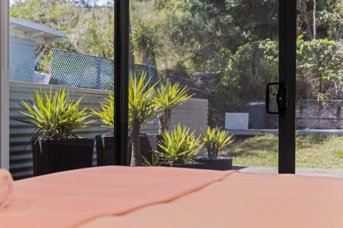 a room with a bed and a window with plants at Breath taking Bay Views Private Pad Spacious in Morisset East