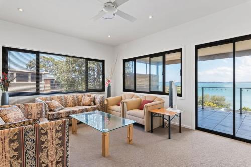 a living room with couches and a table and windows at Breath taking Bay Views Private Pad Spacious in Morisset East