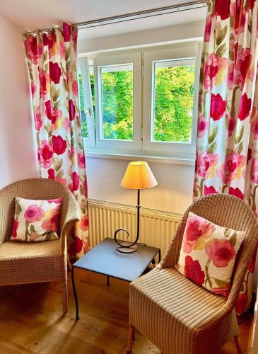 a living room with two chairs and a table and windows at Hotel Fischerhaus in Starnberg