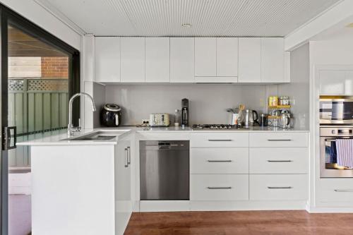 a white kitchen with white cabinets and a sink at Catalina Bay - Child & Pet Friendly in Rathmines