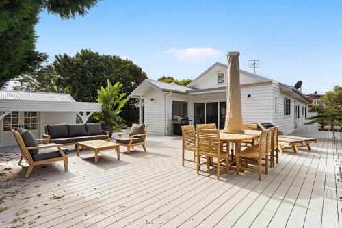 a patio with chairs and tables and a house at Hillside Hamptons Indoor Fire and Fire Pit in Terrigal