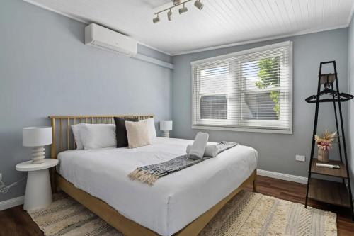 a bedroom with a large white bed and a window at Blue Wren Cottage on Edith - A Fireside Retreat in Wine Country in Cessnock