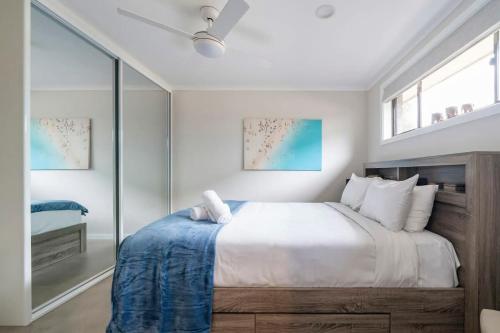 a white bedroom with a large bed and windows at Oak Retreat Bliss by the Beach in Warriewood