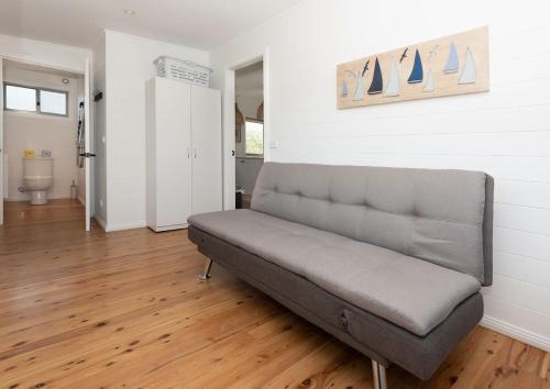 a couch sitting in a living room with a wooden floor at Beachfront Bliss Broulee in Broulee