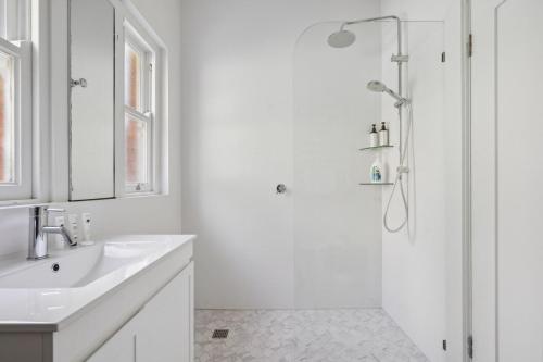 a white bathroom with a shower and a sink at Blu Ocean Views in Collaroy