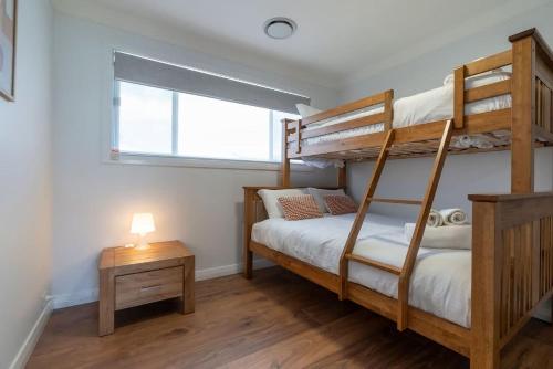 a bedroom with two bunk beds and a window at Beautiful Beach House in Shellharbour