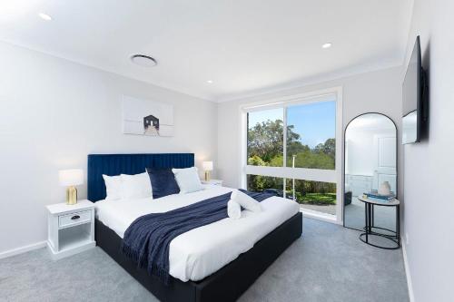 a bedroom with a large bed and a large window at Four Palms Forster Luxe Spacious Pet Friendly in Forster