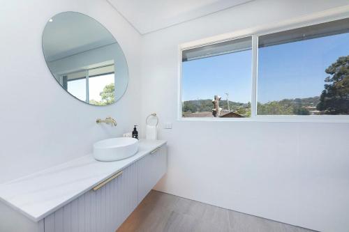 a white bathroom with a sink and a mirror at Four Palms Forster Luxe Spacious Pet Friendly in Forster