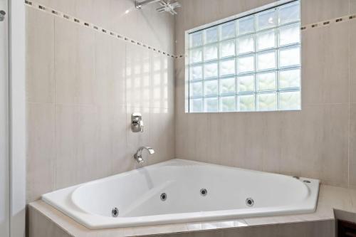 a white bath tub in a bathroom with a window at Waterfront Treetops Getaway in Wangi Wangi