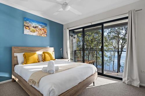 a bedroom with blue walls and a large bed with yellow pillows at Waterfront Treetops Getaway in Wangi Wangi