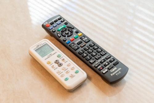 two remote controls and a scale on a bed at 103新大阪15分,下新庄8分の静かで快適な貸切1ルーム in Osaka