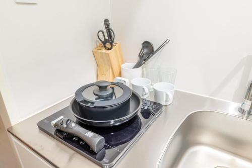 a pot on top of a stove next to a sink at 103新大阪15分,下新庄8分の静かで快適な貸切1ルーム in Osaka