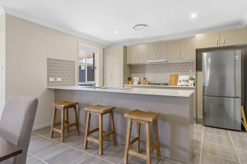 a kitchen with a stainless steel refrigerator and stools at Vineyard Oasis Heart of the Hunter in Cessnock