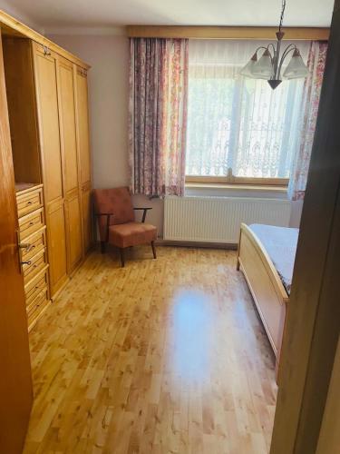 a bedroom with a bed and a chair and a window at Haus LINDE Görtschitztal in Sankt Veit an der Glan
