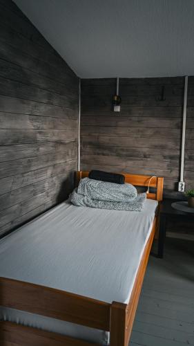 a bed in a room with a wooden wall at ILSA camping in Bauska