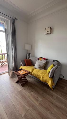 - un canapé avec une couverture jaune dans le salon dans l'établissement Face à la mer, Trouville sur mer, à Trouville-sur-Mer